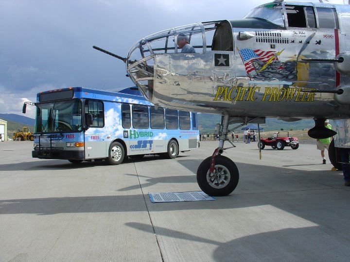 A Steamboat City bus on the runway next to a parked airplane